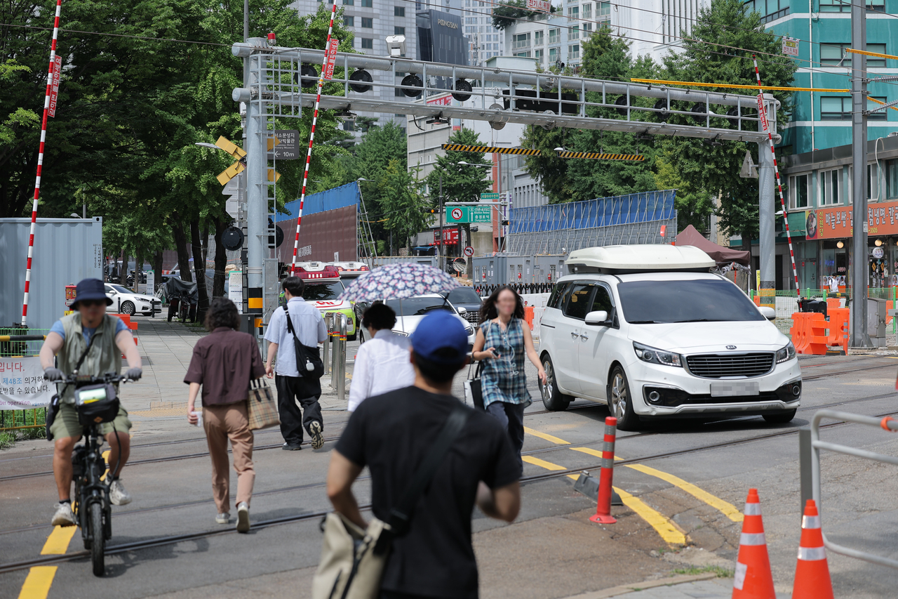 People and cars cross the railroad beneath the Seosomun overpass in Seoul on Saturday after traffic under the overpass fully reopened following the completion of its demolition. (Yonhap)