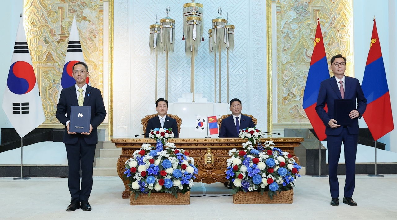 Hwang Ki-yeon (standing at left), president of Korea Eximbank, and Orkhon Onon (standing at right), CEO of Mongolia's Trade and Development Bank, pose for a photo with South Korean President Lee Jae Myung (seated at left) and Mongolian President Ukhnaa Khurelsukh after a signing ceremony during the Korea-Mongolia Business Forum in Ulaanbaatar on Thursday. (Korea Eximbank)
