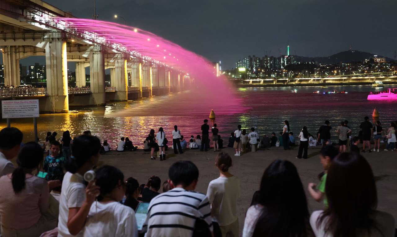 People watch the Banpo Bridge's Moonlight Rainbow Fountain along the Han River in Seoul on Sunday. (Yonhap)