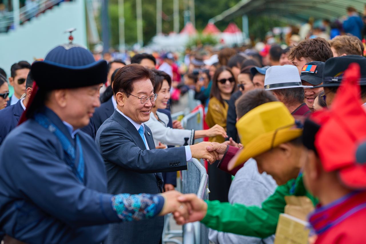 President Lee Jae Myung and first lady Kim Hye Kyung greet spectators alongside Mongolian President Ukhnaagiin Khurelsukh at the Naadam Festival grounds in Ulaanbaatar on Saturday during their state visit to Mongolia. (Pool photo via Yonhap)