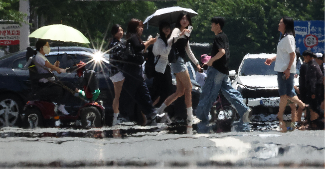 People use umbrellas to shade themselves from the sun in Daegu on Saturday. (Yonhap)