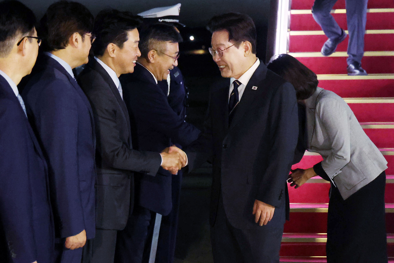 President Lee Jae Myung shakes hands with presidential chief of staff Kang Hoon-sik upon arriving at Seoul Air Base in Seongnam, Gyeonggi Province, on Saturday after concluding a trip that included the NATO summit and a state visit to Mongolia. (Newsis)
