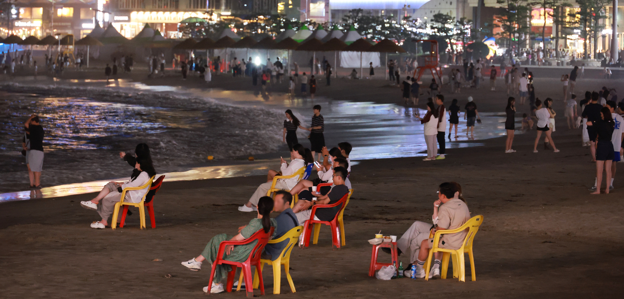 People spend time at Gwangalli Beach in the southern port city of Busan on Sunday, to escape the sweltering heat during a tropical night. (Yonhap)