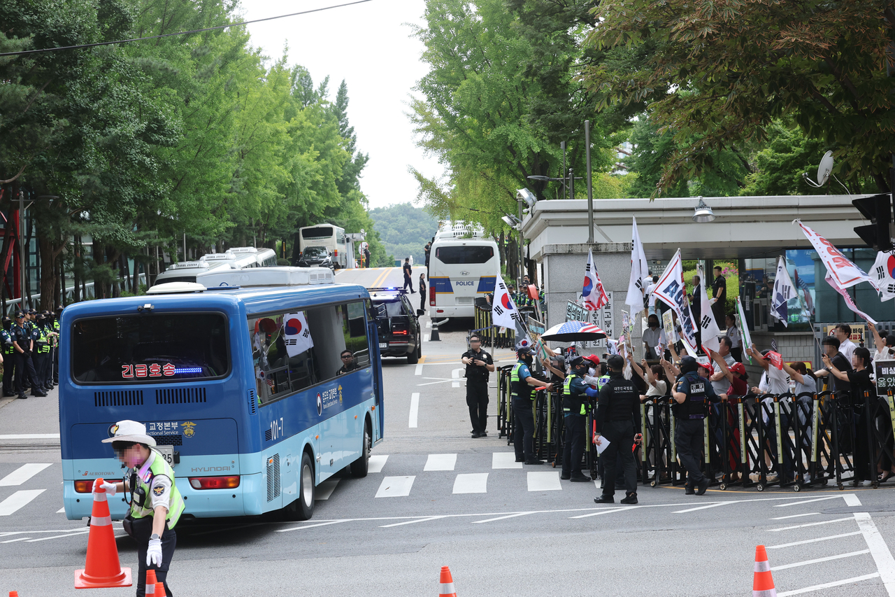 A prison bus thought to be carrying former President Yoon Suk Yeol enters the premises of Seoul Central District Court in Seocho-gu, Seoul, on Monday as his supporters rally outside the gate. (Yonhap)