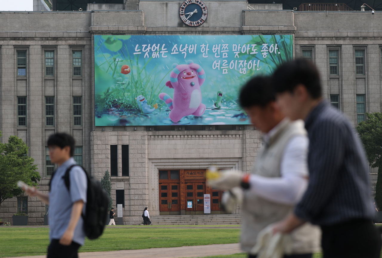 A message reading, "It’s alright to get caught in a sudden shower once in a while. It’s summer!" is displayed on the outer wall of Seoul Metropolitan Library on Monday. (Yonhap)