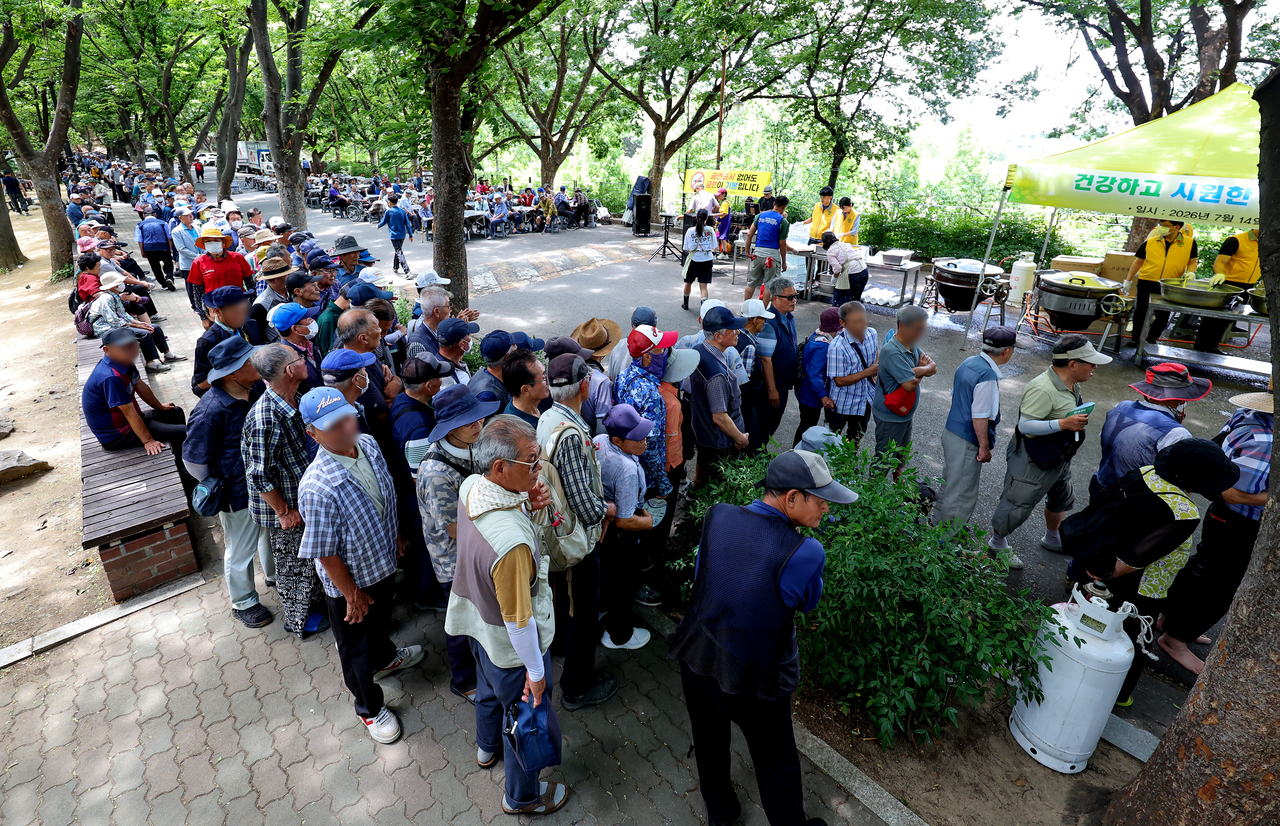 Senior residents line up to receive free bowls of samgyetang at Duryu Park in Daegu on Tuesday, a day before Chobok. (Newsis)