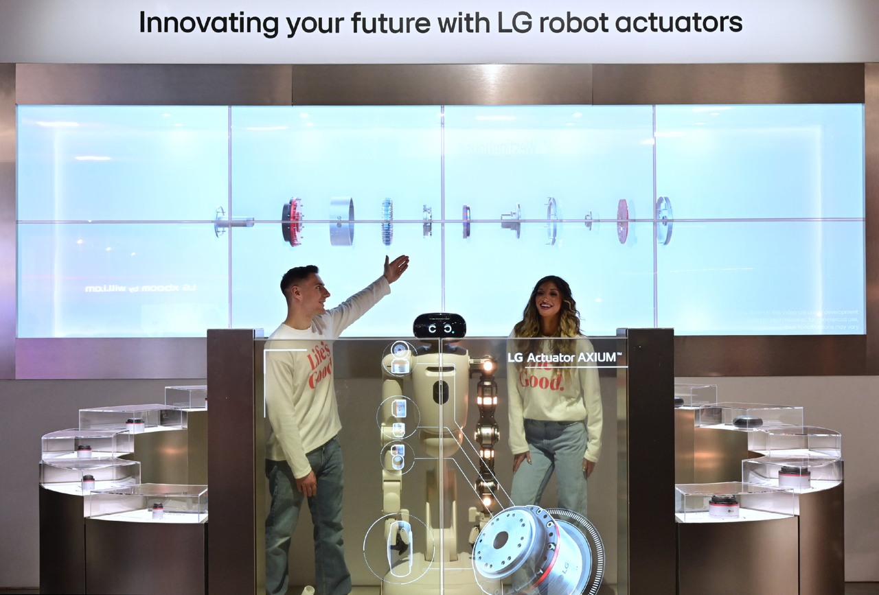 Visitors view LG Electronics' Axium robot actuator lineup and its CLOiD home robot on a transparent OLED display at CES 2026 in Las Vegas in January, where the company introduced the actuator brand it now plans to sell to outside robot manufacturers. (LG Electronics)