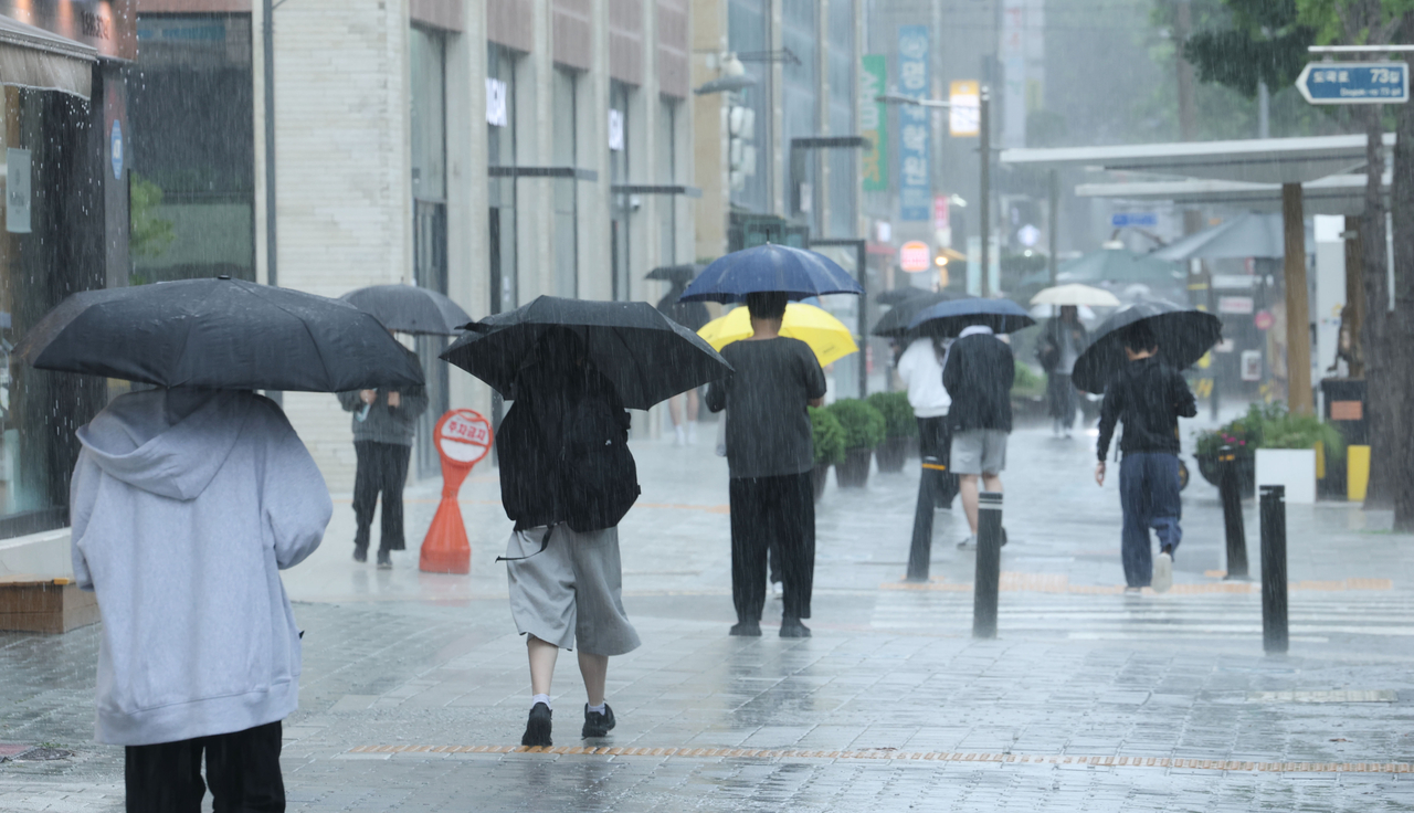 People hold umbrellas to avoid getting wet in the rain on Thursday. (Yonhap)