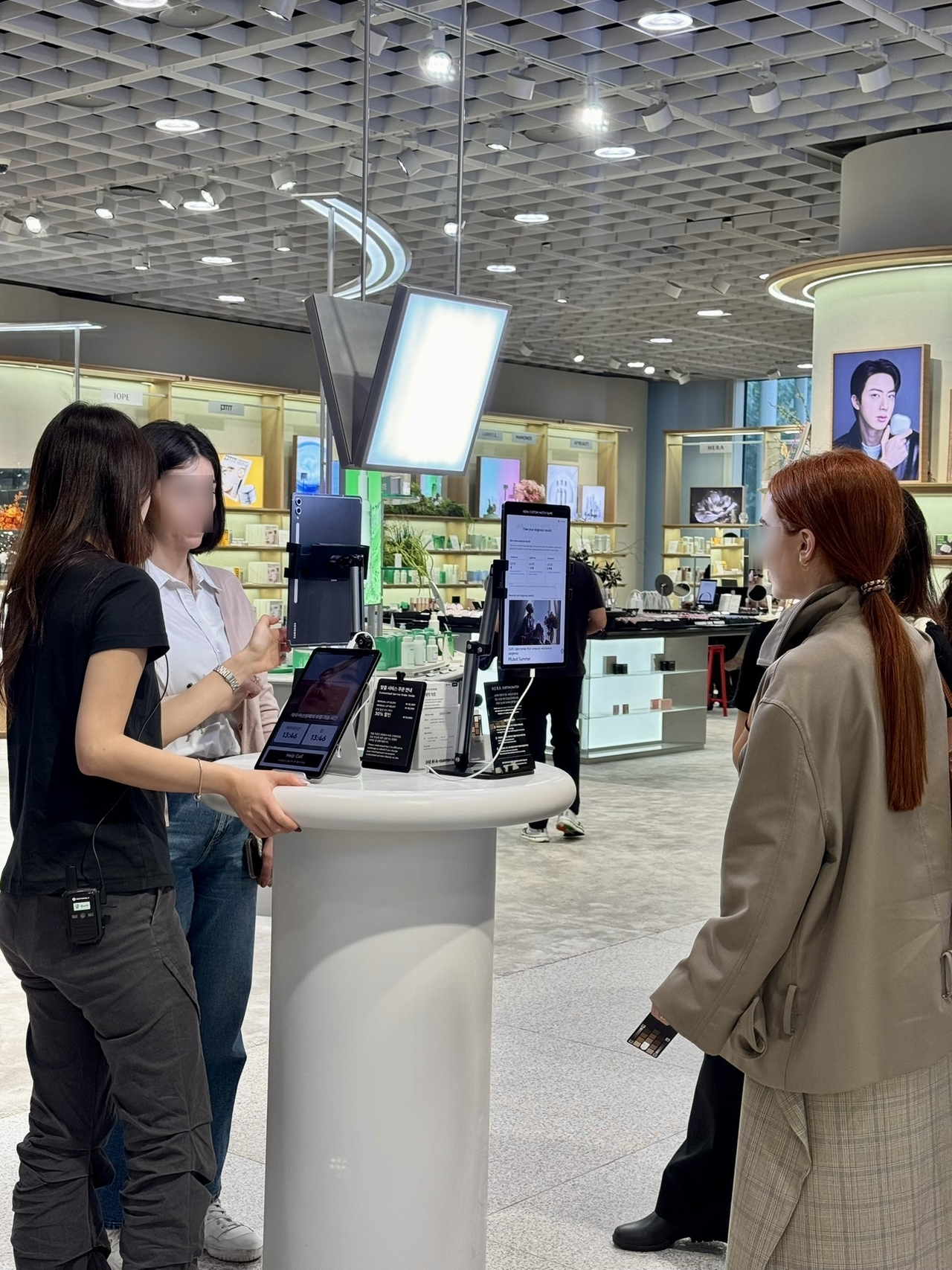 Customers use self-service kiosks with assistance from staff at Amore Yongsan. (No Kyung-min/The Korea Herald)