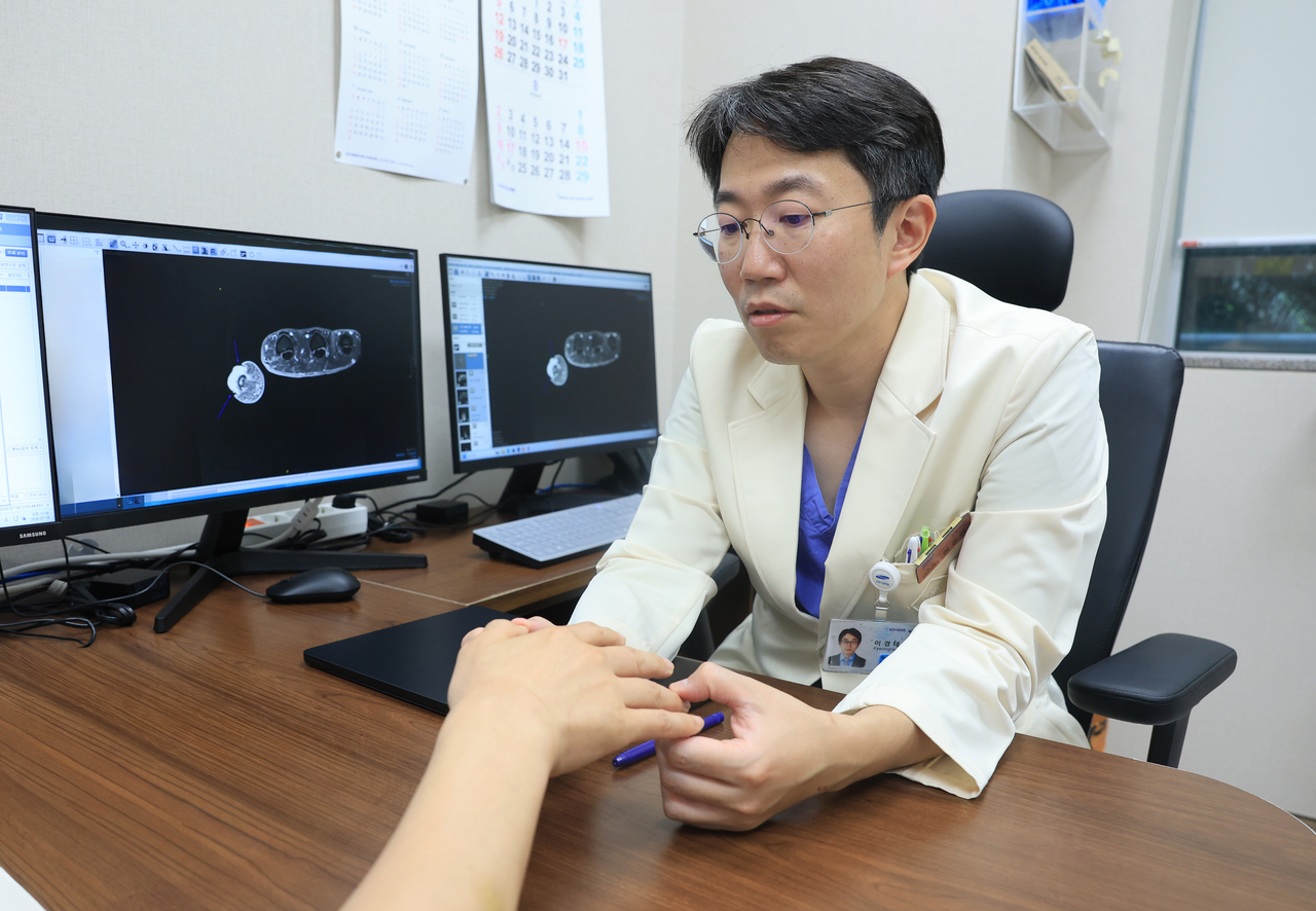 이경태 삼성서울병원 성형외과 교수가 흑색종 환자의 손을 살펴보고 있다