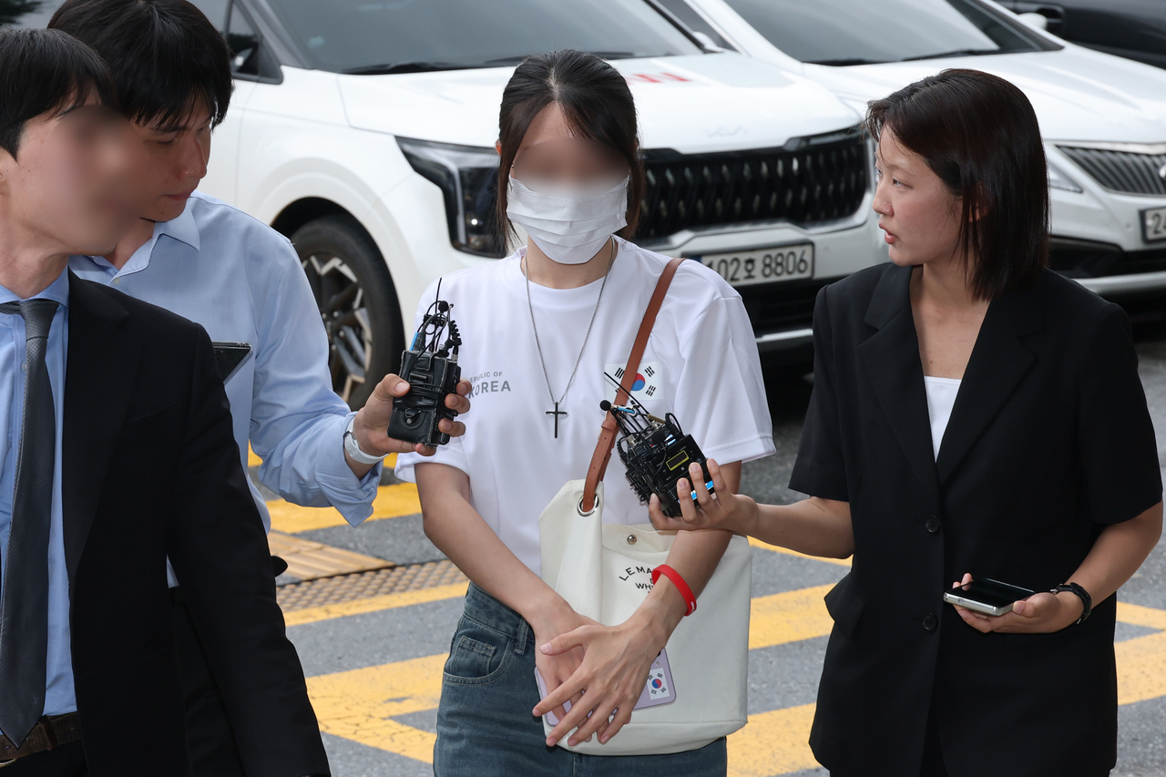 A woman (C), who faces charges of blocking officials of sports organizations under the Korean Sport & Olympic Committee from entering the Olympic Park Handball Gymnasium, arrives at the Seoul Songpa Police Station in southern Seoul to undergo questioning in this photo taken July 10, 2026. (Yonhap)