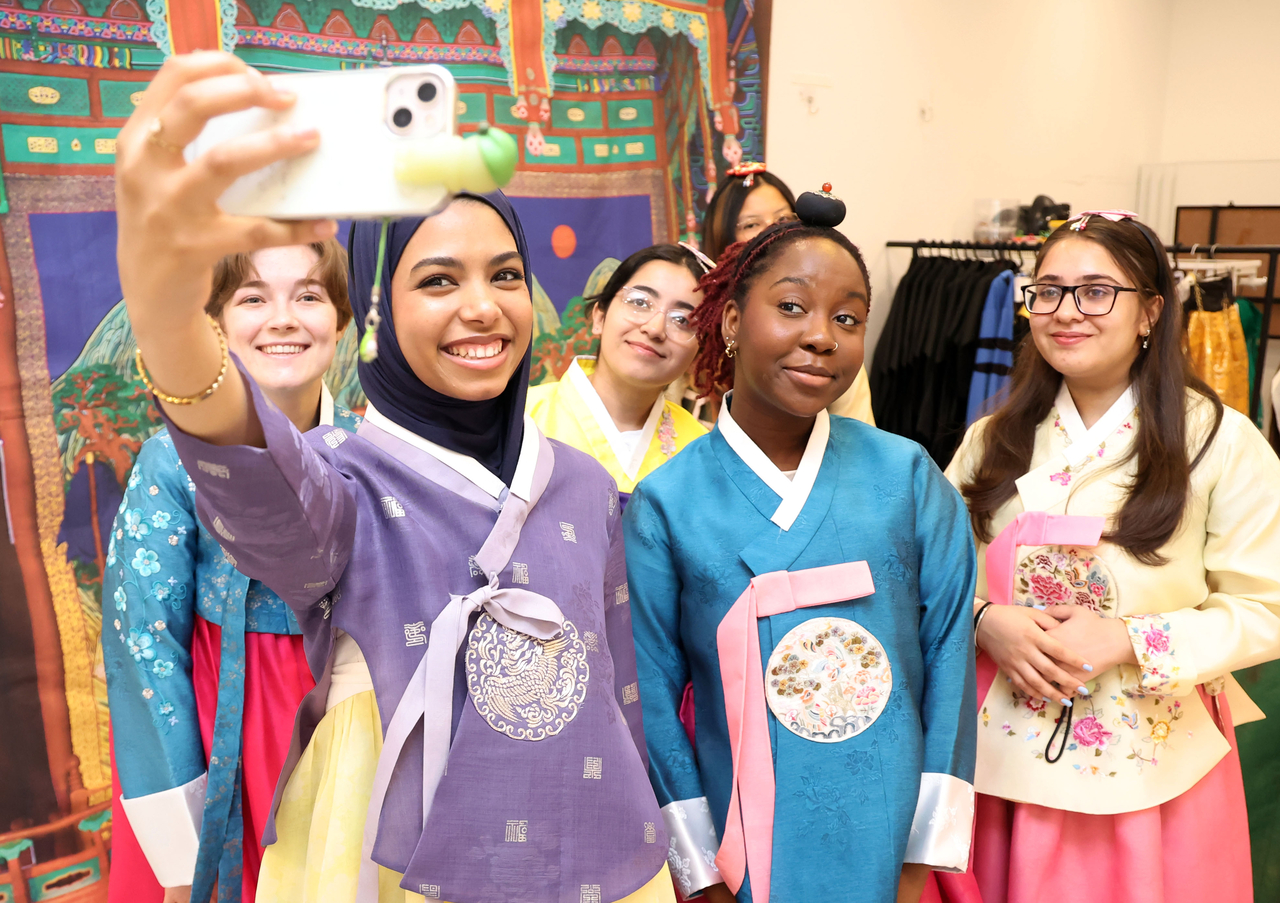 International students clad in hanbok take photos at a culture center in Busan on Thursday. (Newsis)
