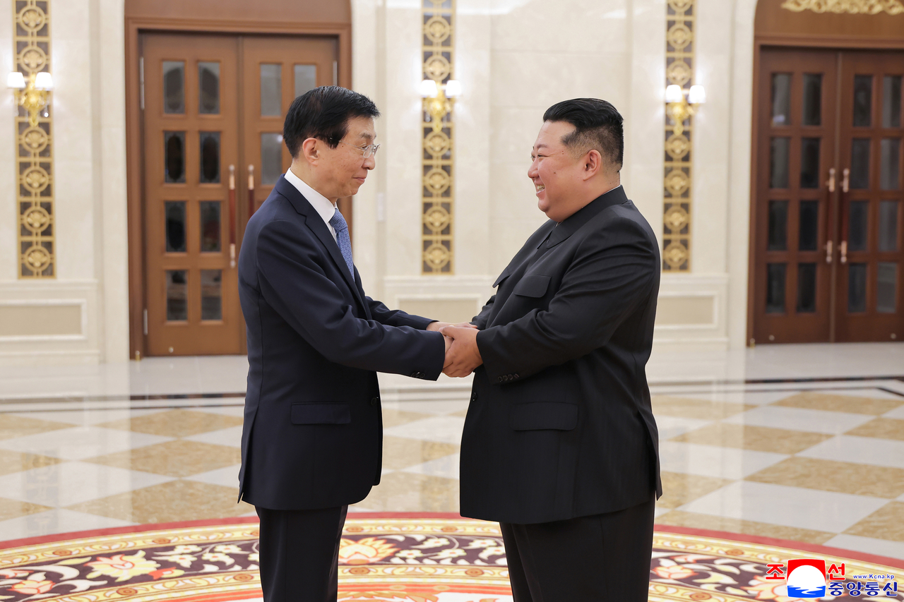 North Korean leader Kim Jong-un (right) shakes hands with Wang ‌Huning, China's fourth-highest-ranked official in Pyongyang, in this photo released by the state-run Korean Central News Agency reported on Friday. (Yonhap)