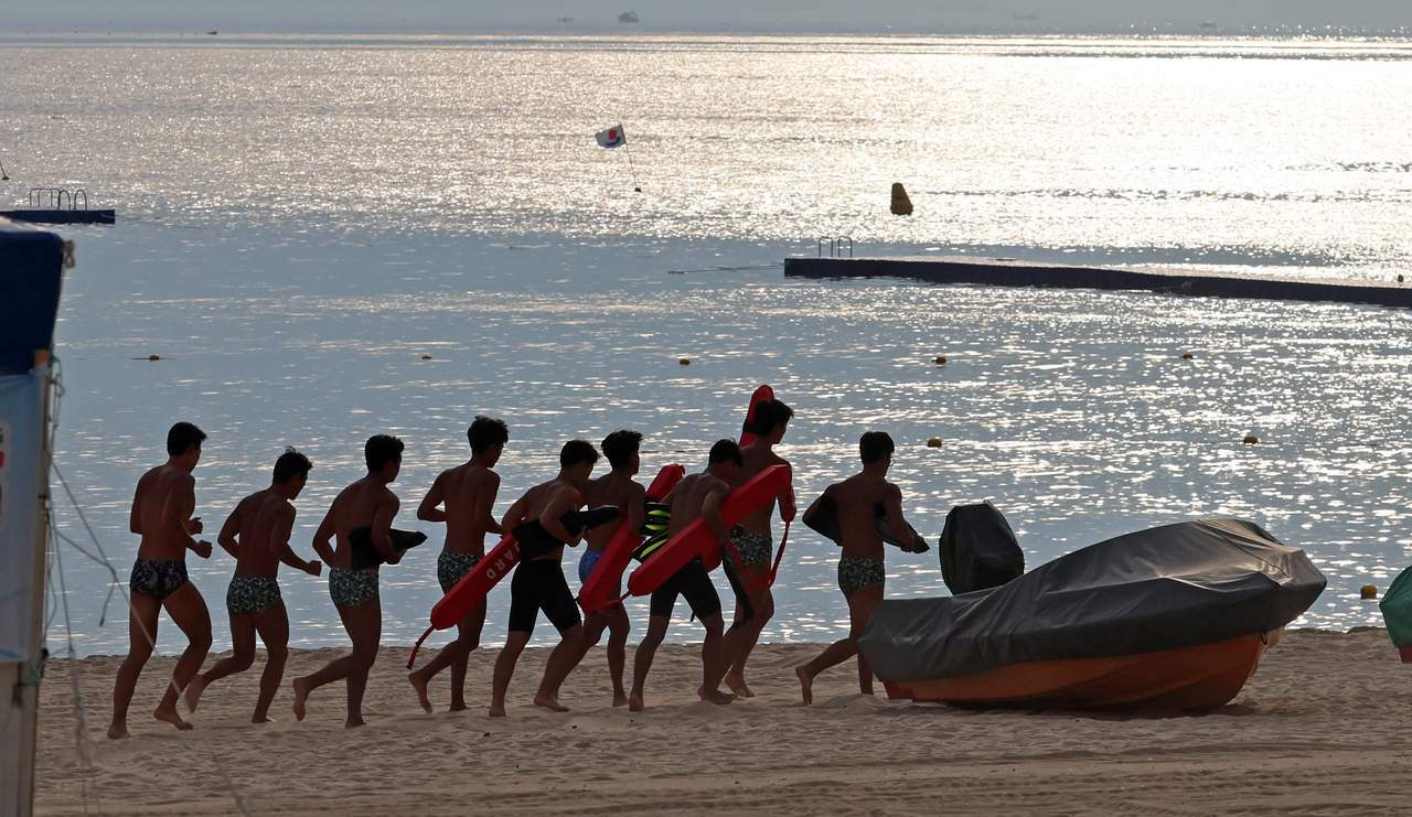 Lifeguards run across the sand at Gyeongpo Beach in Gangneung, Gangwon Province, during early-morning training on Friday.   (Yonhap)