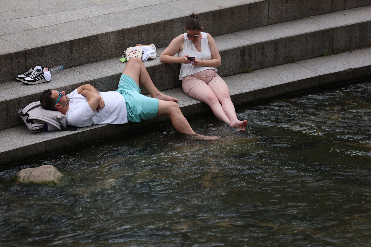 Two people relax next to the Cheonggyecheon in Seoul on July 13. (Yonhap)