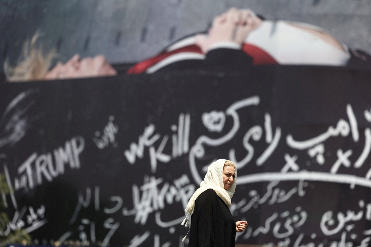 A woman walks next to a billboard depicting US President Donald Trump laid in a coffin, in Tehran, Iran on July 18. (West Asia News Agency via Reuters-Yonhap)