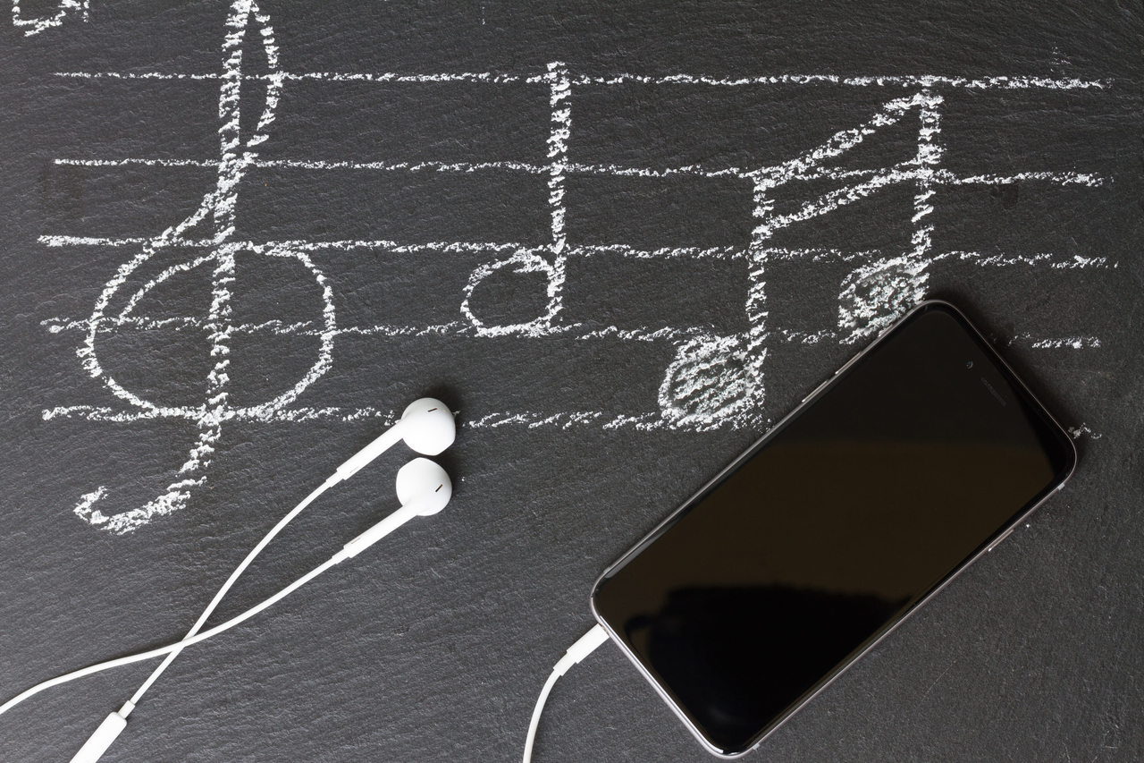 Music notes with treble clef, modern phone and headphones (123rf)