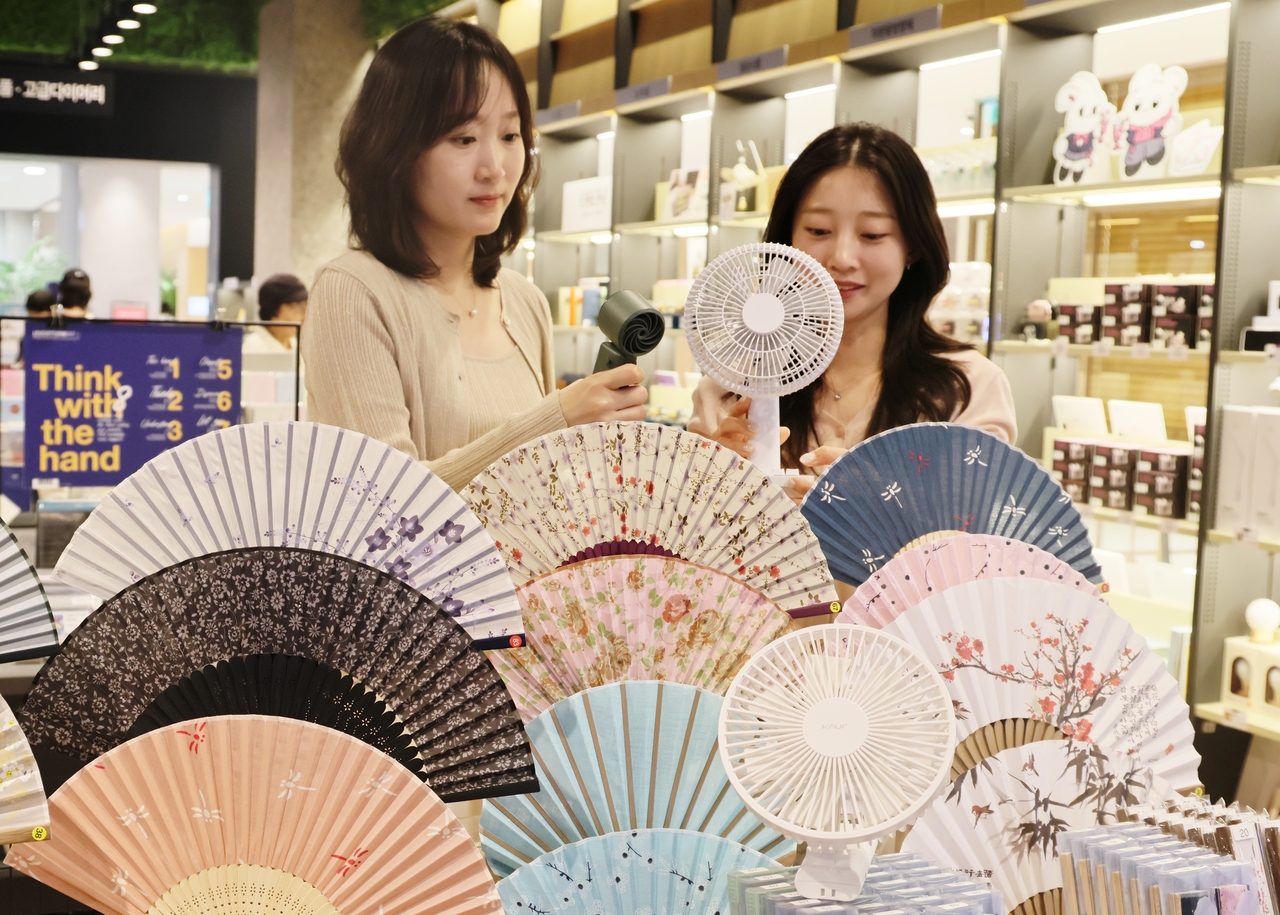 Staff display a range of summer cooling products, including hand fans and portable electric fans, at Kyobo Book Centre & Hot Tracks on the seventh floor of Lotte Department Store's Sangin branch in Daegu. [Lotte Department Store]