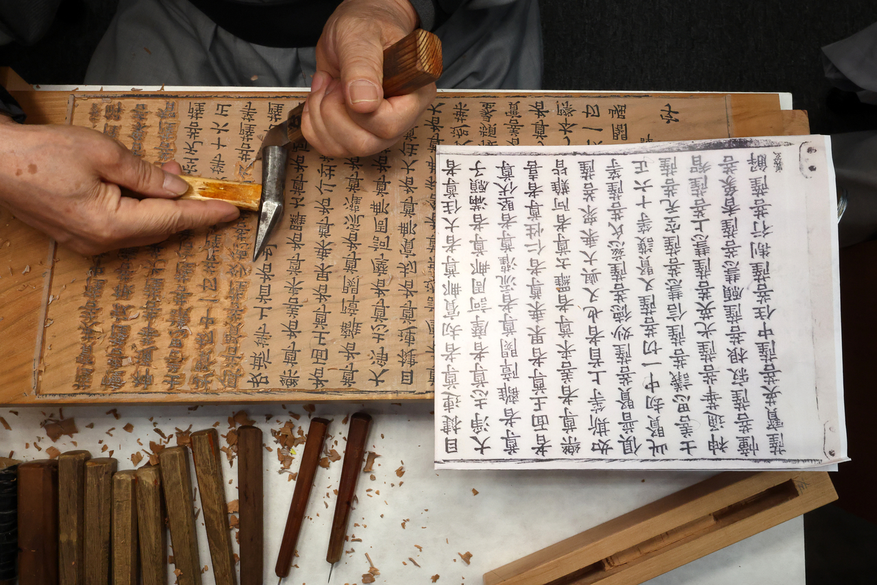 A Buddhist monk demonstrates the woodblock carving process at the K-Heritage House during the 48th session of the UNESCO World Heritage Committee at Bexco in Busan on Monday. (Yonhap)