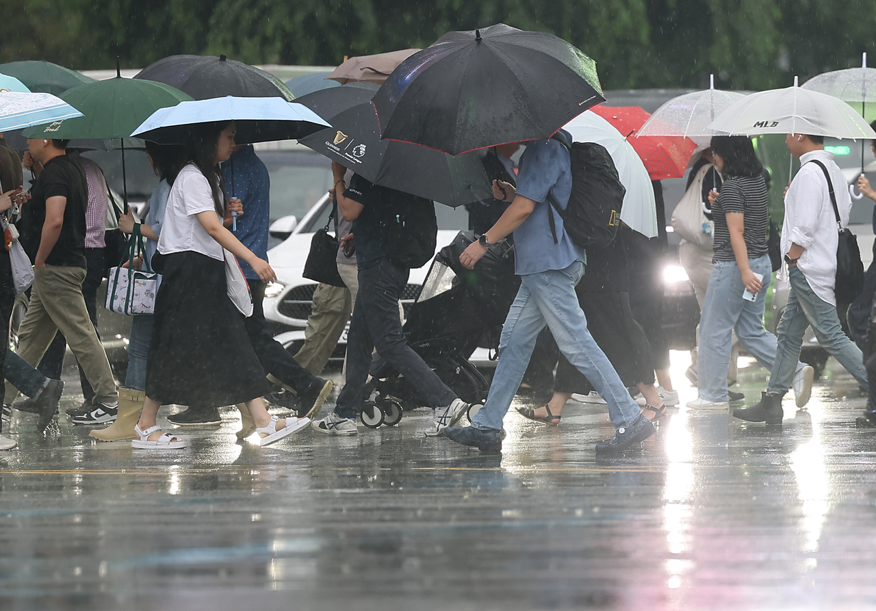 People cross a road in the rain in central Seoul on Monday. (Yonhap)