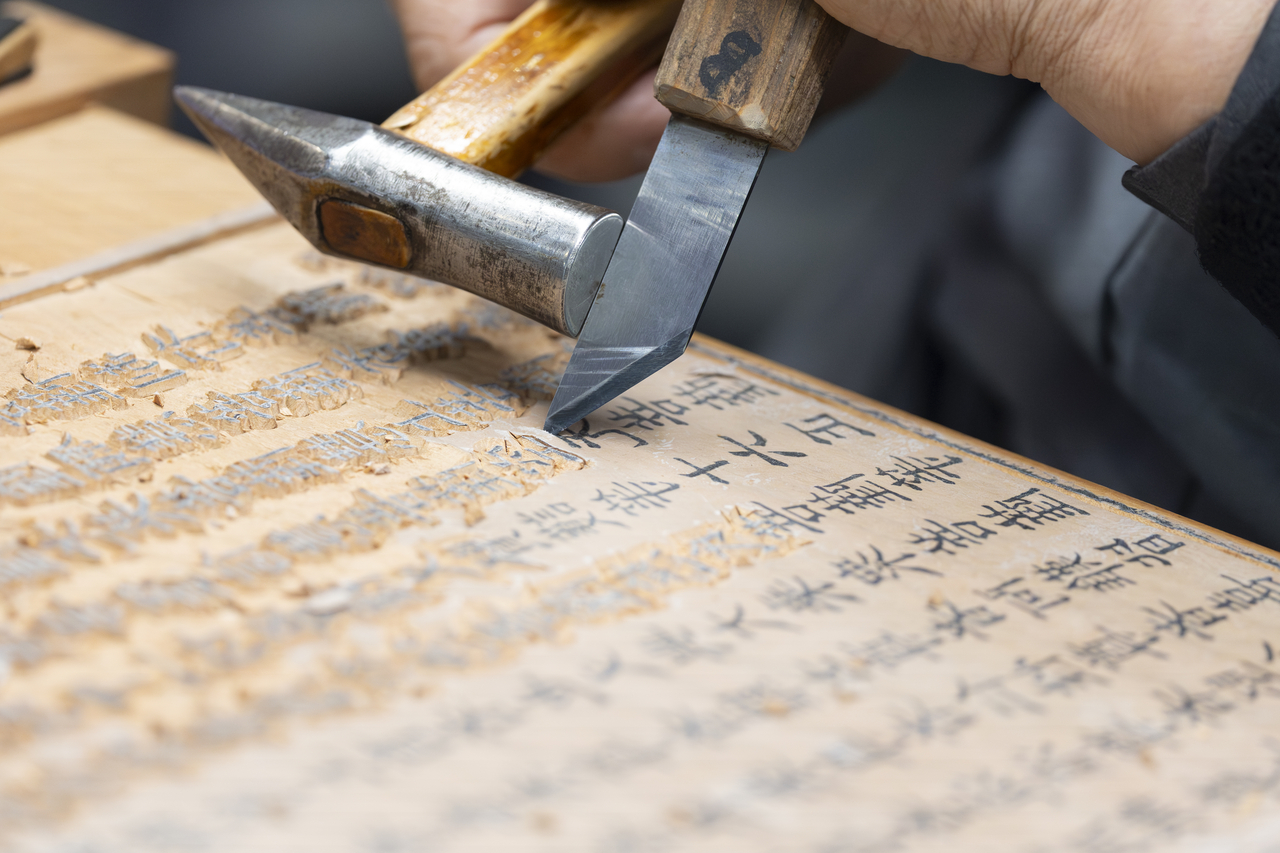 A Buddhist monk demonstrates the woodblock carving process at the K-Heritage House during the 48th session of the UNESCO World Heritage Committee at Bexco in Busan on Monday. (Yonhap)