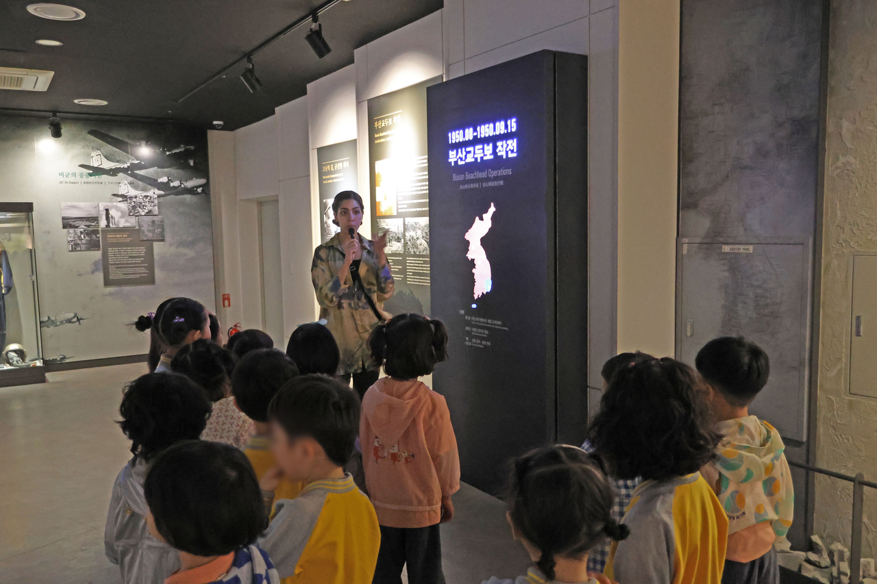 Sherry Nasrat (center), a 23-year-old Egyptian student at Pusan National University, guides a group of Korean children through an exhibition at the UN Peace Memorial Hall. (UN Peace Memorial Hall)