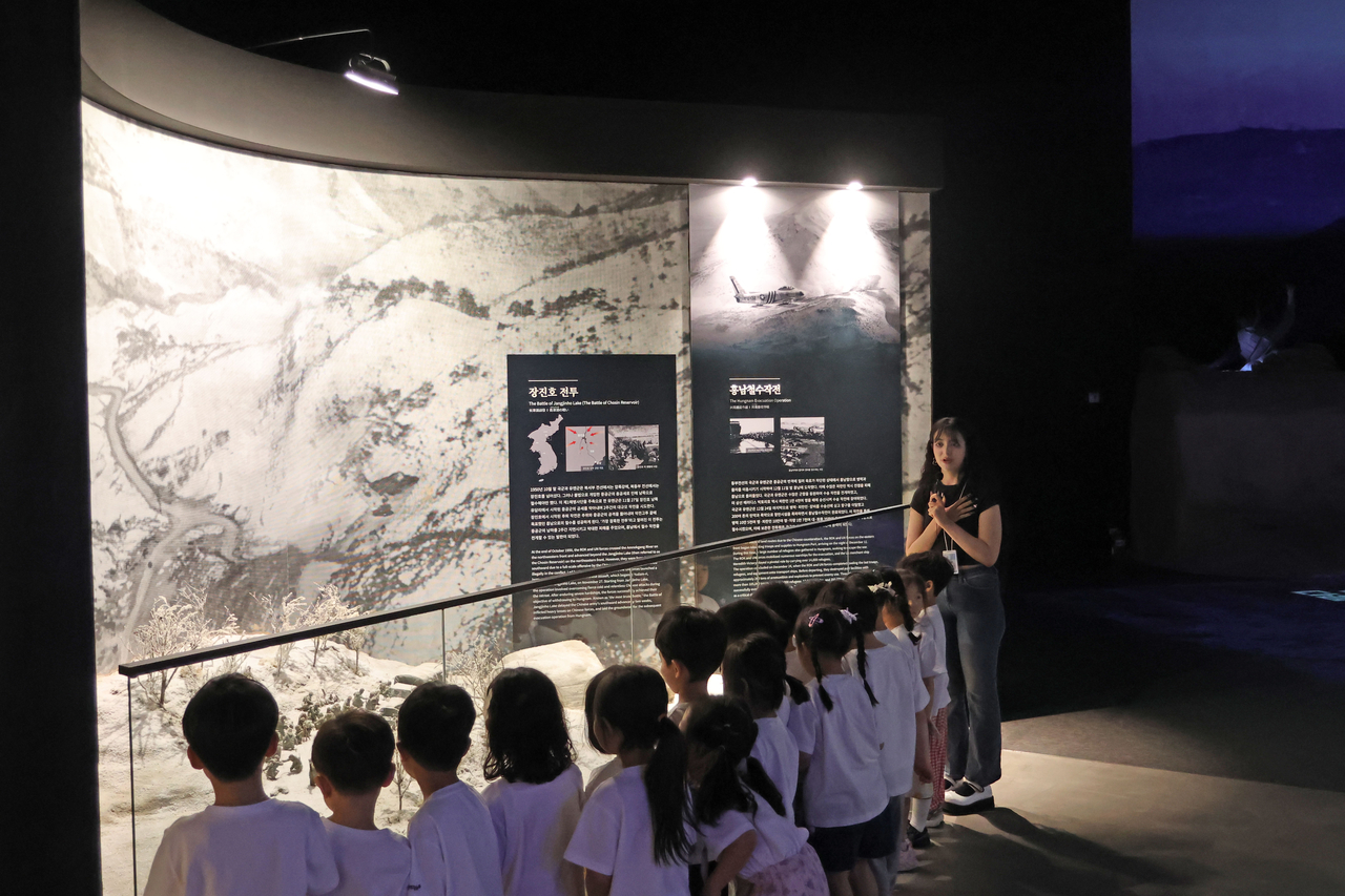 Carma Elharazi (first from right), a 25-year-old student, leads a group of children through an exhibition at the UN Peace Memorial Hall. (UN Peace Memorial Hall)