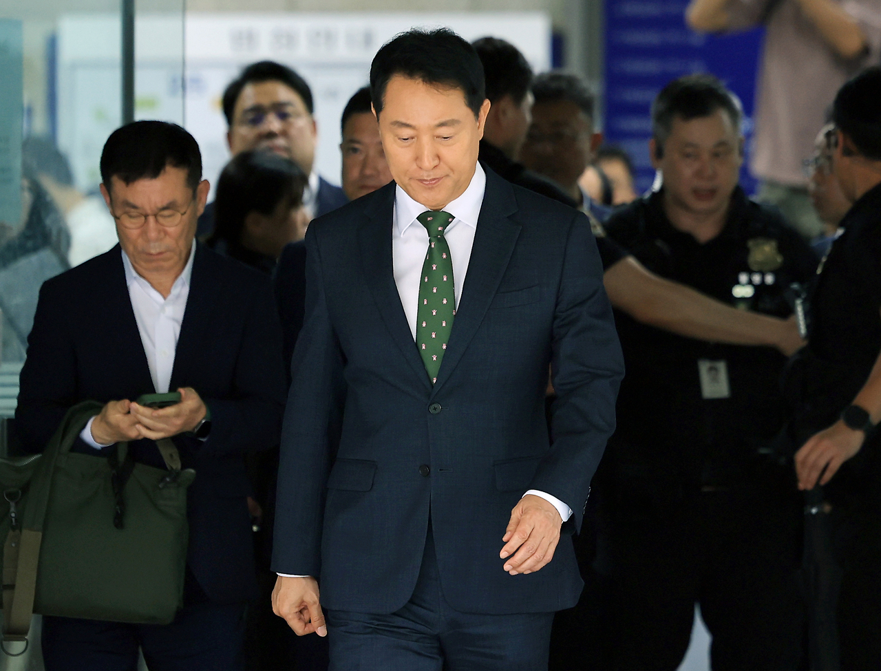 Seoul Mayor Oh Se-hoon (center) leaves the Seoul Central District Court in southern Seoul on Wednesday after being fined 10 million won for violating the Political Funds Act, after being convicted of asking political broker Myung Tae-kyun to conduct opinion polls and having a supporter pay for them during the People Power Party's nomination race for the 2021 Seoul mayoral by-election. (Yonhap)