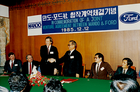 Officials from Mando and Ford pose for a commemorative photo after signing a joint-venture agreement on Dec. 12, 1985. That partnership gave rise to Halla Climate Control in 1986, the predecessor of Hanon Systems. [Hanon Systems]