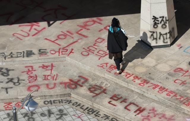A person walks over graffiti protesting a shift to coeducation at Dongduk Women’s University on Feb. 21. (Herald DB)