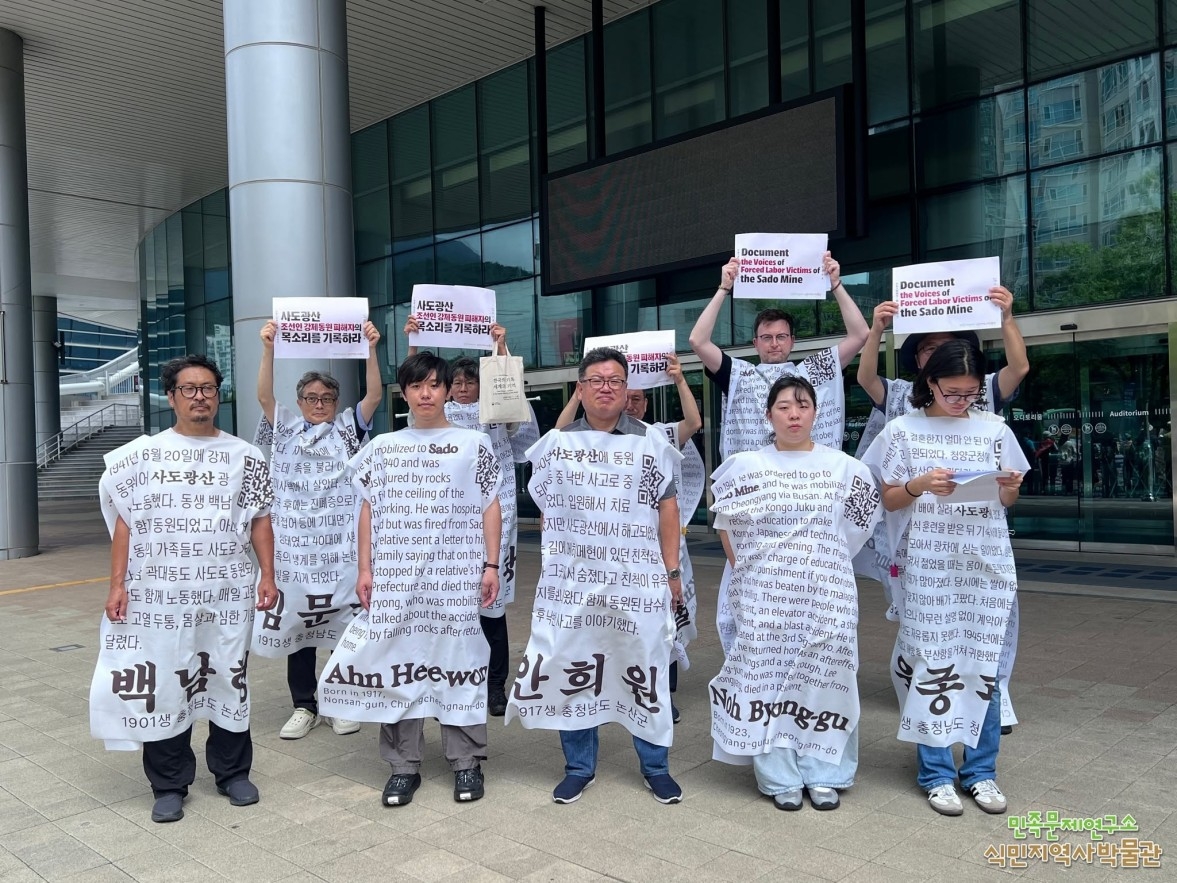 Members of civic groups stage a demonstration near Bexco in Busan on Tuesday, wearing placards bearing the names of Koreans forcibly mobilized to work at Sado mine during Japan's colonial rule. (Yonhap)