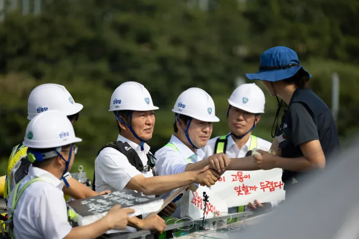 Then-Democratic Party of Korea leader Jung Chung-rae (third from left) holds hands with a laid-off worker (right) staging a rooftop protest in Gumi, North Gyeongsang Province, in August 2025. (Democratic Party of Korea)
