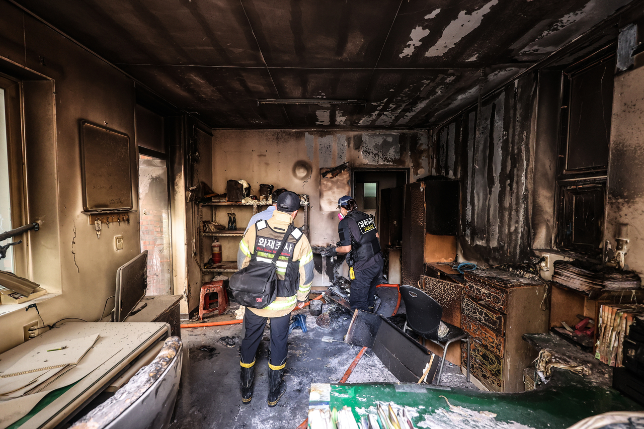 Officials inspect the scene of an explosion and fire at the management office of an apartment complex in Gyeongsan, North Gyeongsang Province, Thursday. (Yonhap)