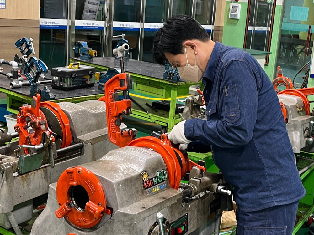 A student practices energy piping work in the piping workshop of the New Middle-Aged Specialized Program at Korea Polytechnics' Suncheon campus. [Korea Polytechnics]