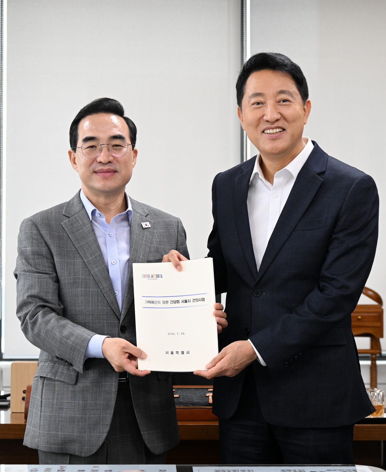 Seoul Mayor Oh Se-hoon delivers a proposal for state funding to support aging infrastructure improvement projects to Minister of Planning and Budget Park Hong-keun (left) at the Korea Public Finance Information Service on Friday, posing for a photo after the meeting. [Seoul Metropolitan Government]