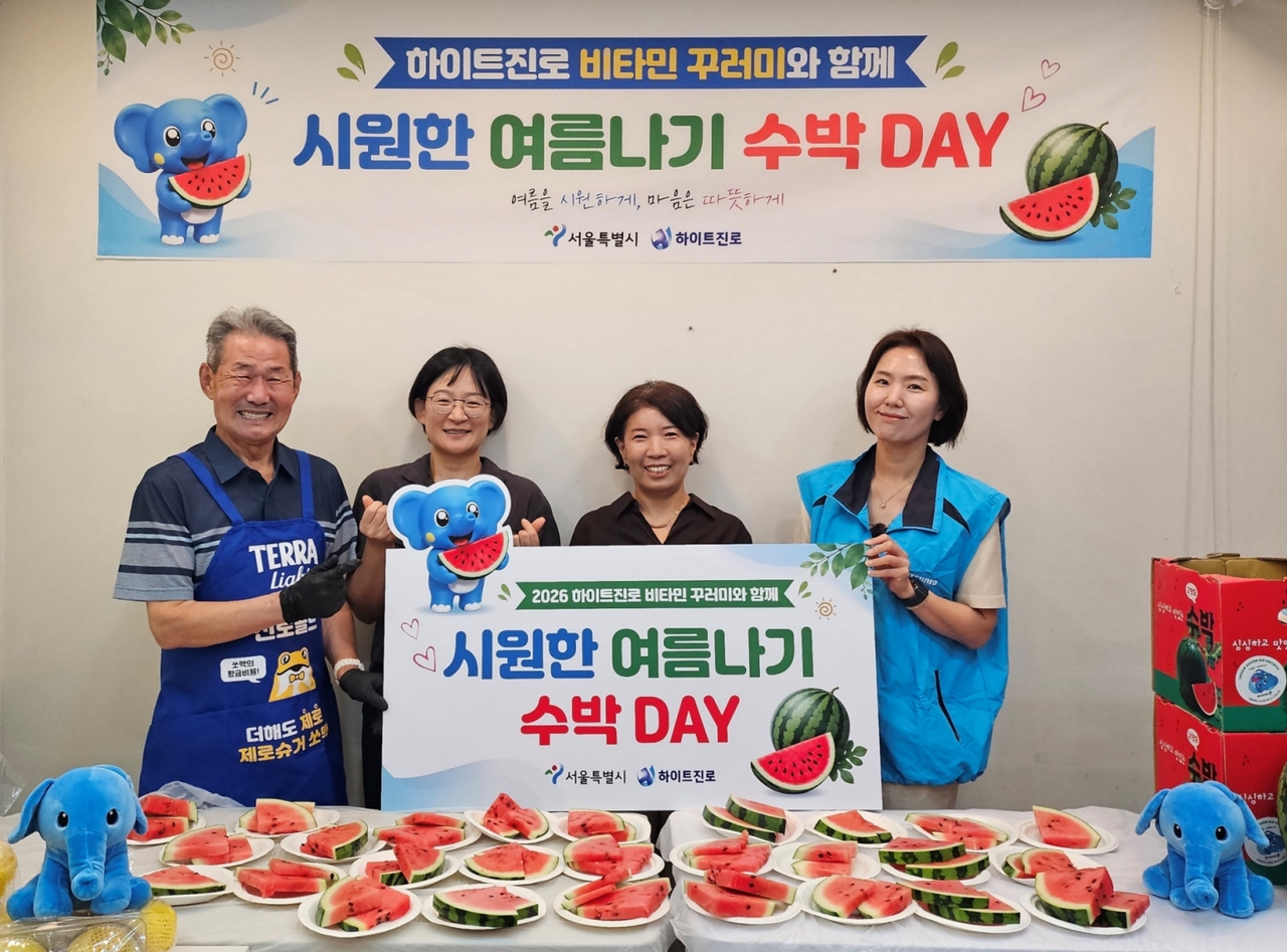 지난 22일 서울역 쪽방촌에서 2026 하이트진로 비타민 꾸러미와 함께 시원한 여름나기 ‘수박 DAY’ 행사가 열렸다. (왼쪽부터) 쪽방촌 주민, 서울시 이신옥 팀장, 서울역 쪽방상담소 유호연 소장, 하이트진로 관계자가 기념 촬영을 하고 있다. [하이트진로 제공]