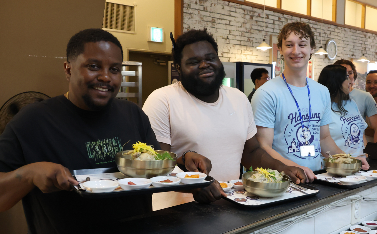 International students pose with samgyetang, a chicken dish traditionally eaten during the hottest days of summer, as part of a program at Hansung University in Seoul on July 14. (Yonhap)