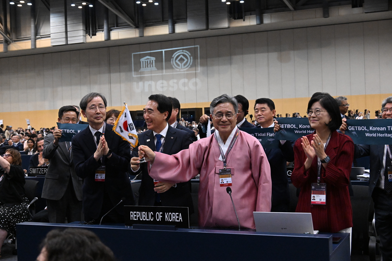 Huh Min, second from right, administrator of the Korea Heritage Service, waves Korea's national flag with Park Soo-hyun, third from right, governor of South Chungcheong Province, following the expanded inscription of "Getbol, Korean Tidal Flats (Phase II)" as a UNESCO World Heritage site during UNESCO's plenary session at Bexco in Busan, Saturday. (Korea Heritage Service)