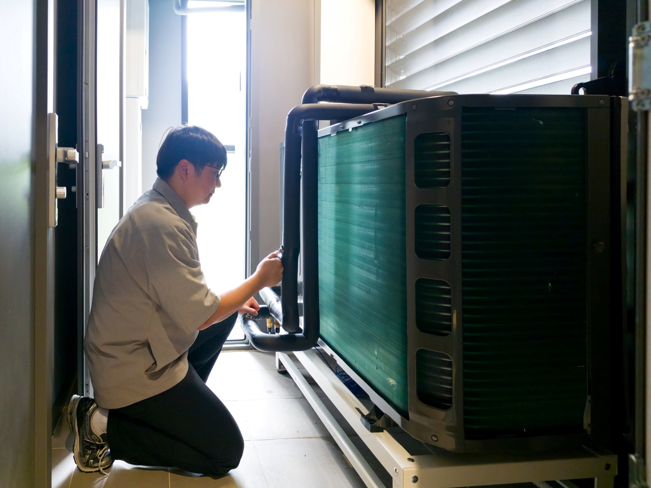 Samsung Electronics is conducting a pilot of its "EHS All-in-One" high-efficiency heat pump in an apartment-style environment. A Samsung Electronics employee inspects the unit installed at the residential performance research lab. [Samsung Electronics]