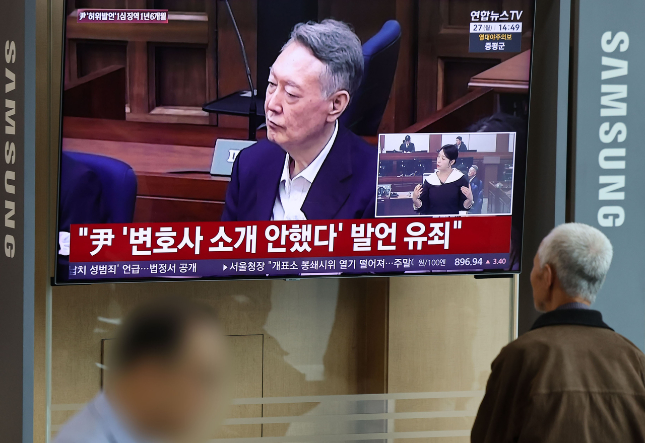 A passerby watches the news as the Seoul Central Court on Monday handed a guilty verdict to ex-President Yoon Suk Yeol for violating election law. (Yonhap)