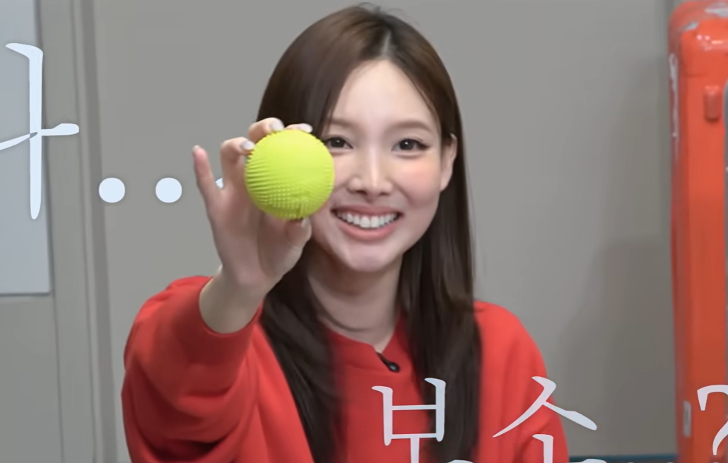 Twice's Nayeon holds up her massage ball. (YouTube)