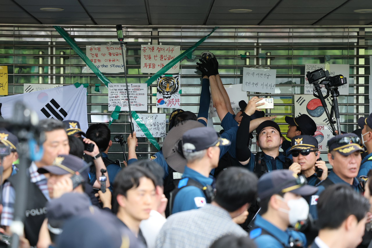 지난 2일 국회 ‘제9회 전국동시지방선거 투표용지 부족 사태 등 국민 참정권 침해 진상규명 및 선거관리 개혁을 위한 국정조사 특별위원회’ 현장 조사가 예정된 서울 송파구 올림픽공원 핸드볼경기장 개표소에서 경찰 기동대가 출입구에 쌓인 물건을 치우며 문을 열고 있다. [연합]