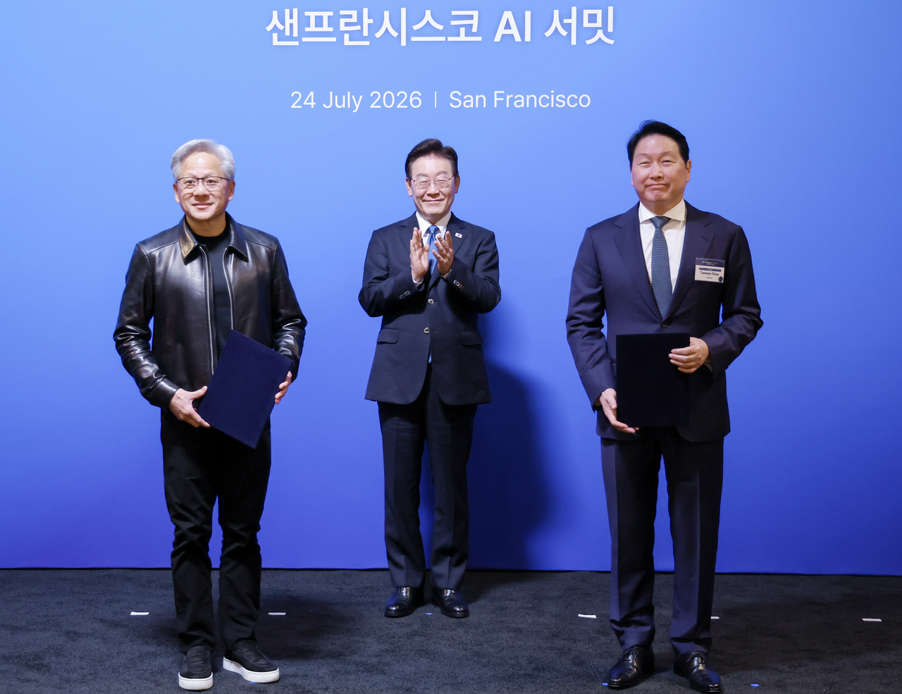 최태원(오른쪽) SK 회장과 젠슨 황(왼쪽) 엔비디아 최고경영자가 24일(현지시간) 이재명(가운데) 대통령이 임석한 가운데 미국 샌프란시스코 더 미드웨이에서 열린 AI 서밋에서 SK하이닉스, SKT와 엔비디아의 전략적 AI 팩토리 및 반도체 협력 MOU를 체결한 뒤 기념촬영을 하고 있다. [연합]