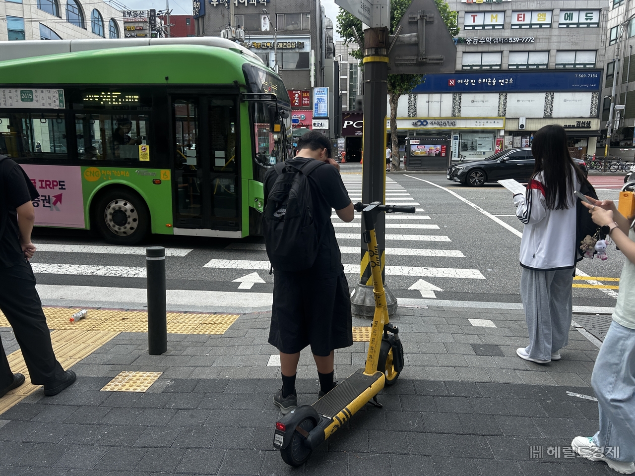 A man waits at a crosswalk without a helmet while riding an e-scooter in the hagwon district of Daechi-dong, Gangnam-gu, Seoul, on Monday. [Lee Jun-young/The Herald Business]