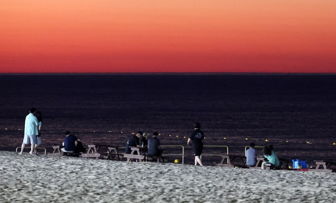 People sit on the beach at sunset in Gangneung, Gangwon Province, on July 15. (Yonhap)