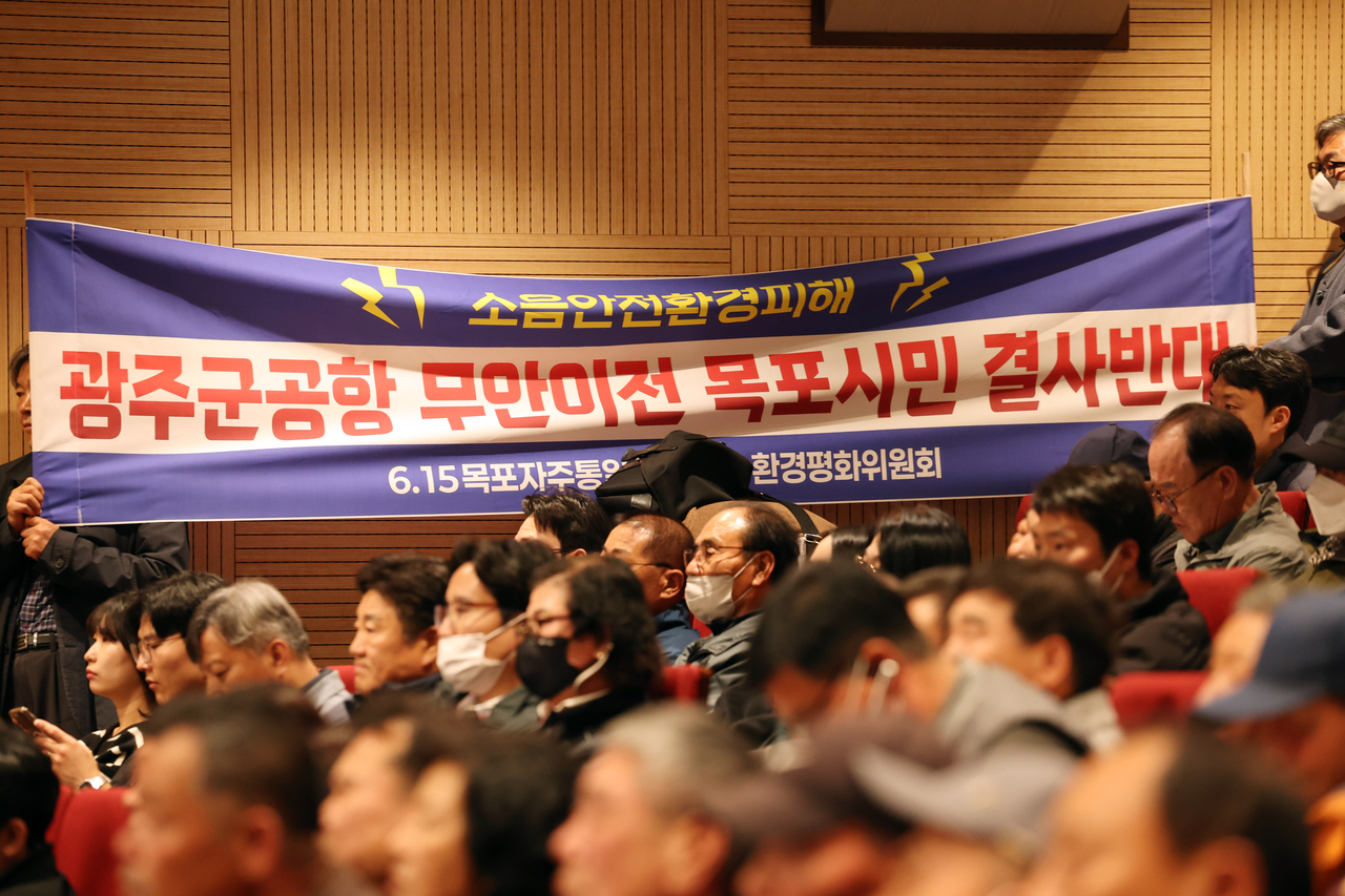 전남 무안군 승달문화예술회관 대강당에서 열린 광주 군공항 주민 설명회에서 시민단체 관계자들이 군공항 이전 반대 현수막을 들고있다. <연합뉴스>