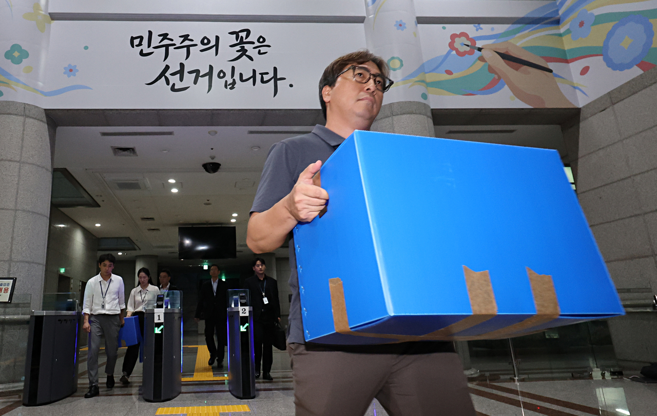지난 23일 경기도 과천 중앙선거관리위원회 압수수색을 마친 검경 합동수사본부 관계자들이 선관위 건물에서 나오고 있다. [연합]