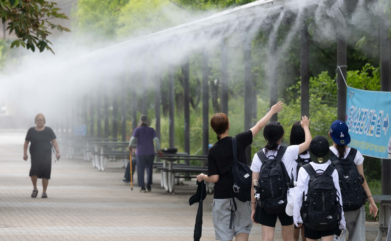 Residents walk through a cooling mist at Ttukseom Hangang Park in Gwangjin-gu, Seoul. (Yoon Chang-bin)