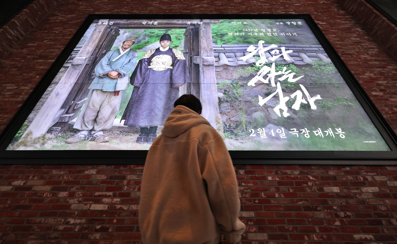 서울 한 영화관에서 한 방문객이 ‘왕과 사는 남자’ 포스터를 보고 있다. [연합]