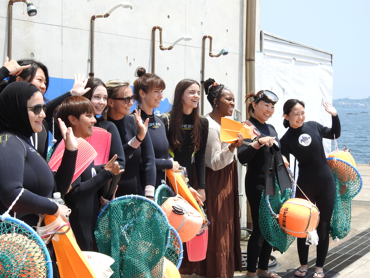 International visitors pose for a photo before taking part in an experience with female divers known as haenyeo during a working vacation program on Jeju Island on June 29. (Newsis)